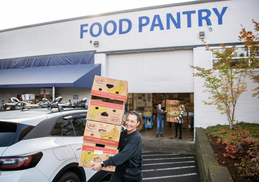 Baylie Phillips helps carry banana boxes back to a vehicle to collect more food Tuesday at FISH of Vancouver. (Taylor Balkom/The Columbian)