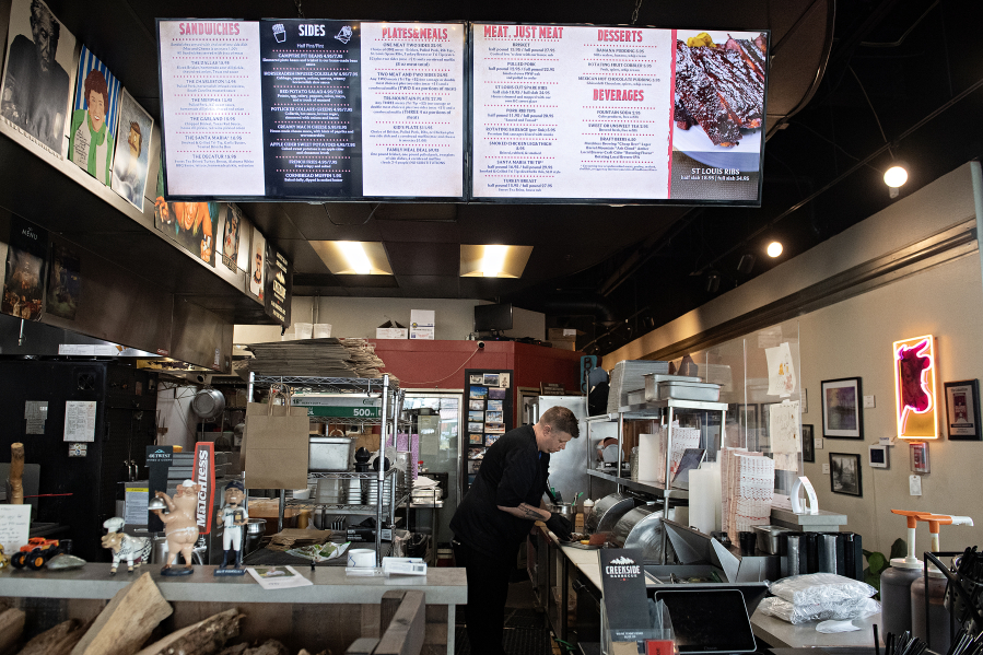 Steven Hollifield of Creekside Barbecue works behind the front counter as he prepares to feed local residents as part of a free meal program. The restaurant saw 400 people looking for a hot meal last week. (Amanda Cowan/The Columbian)
