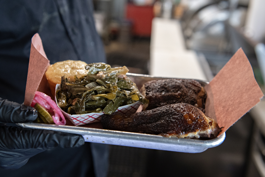 Steven Hollifield of Creekside Barbecue holds a plate featuring smoked chicken, a side dish and cornbread. Multiple restaurants and community members are providing free meals and food to those impacted by the SNAP benefit cuts. (Amanda Cowan/The Columbian)