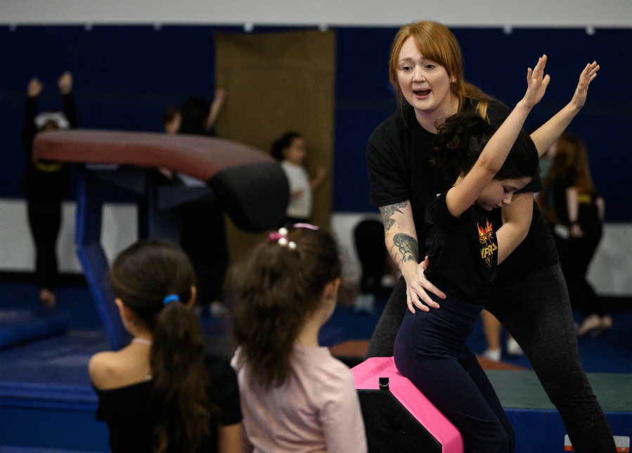 Camas Washougal Youth Cheer co-founder Crista Braun, right, works with Lucille Shafir to show other students how to tumble backward Sunday at VEGA Gymnastics in Washougal. (Taylor Balkom/The Columbian)