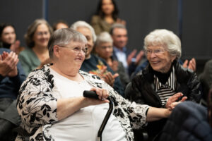Sharon Wodtke, left, smiles as she holds her sister Patti Taylor’s hand and applause breaks out Wednesday during a Clark County Commission on Aging meeting at the Clark County Public Service Center. Wodtke, a Battle Ground resident, received the commission’s sixth annual Silver Citizen Award. (Taylor Balkom/The Columbian)