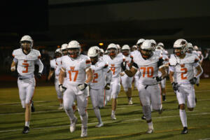Washougal players Logan Lynch (3) Michael Camp (17), Jerae Goodell (70) and Parker Cherry (2) run out onto the field to face Tumwater in a Class 2A football state first-round game at Tumwater District Stadium in Tumwater on Friday. (Tim Martinez/The Columbian)