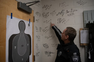 Camas Police Sgt. David Chaney points to a signature on the wall of the armory Nov. 21 at the Camas Police Department headquarters. (Taylor Balkom/The Columbian)