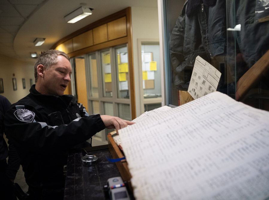 Camas Police Sgt. Dave Chaney points at a name in a historic booking log Nov. 21 at the Camas Police Department headquarters. (Photos by Taylor Balkom/The Columbian)