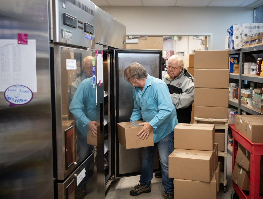 Volunteers George Lee, left, and Robin Hixson load prepared Thanksgiving meals into a freezer at Martha&rsquo;s Pantry. (Taylor Balkom/The Columbian)