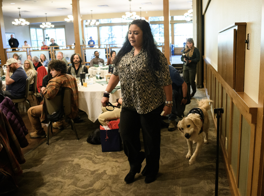 Veteran Jenet Conover, center, walks with her service dog Huck on Friday during a Northwest Battle Buddies graduation ceremony at Royal Oaks Country Club in Vancouver. The organization gave away its 300th dog to a veteran at the ceremony. (Taylor Balkom/The Columbian)