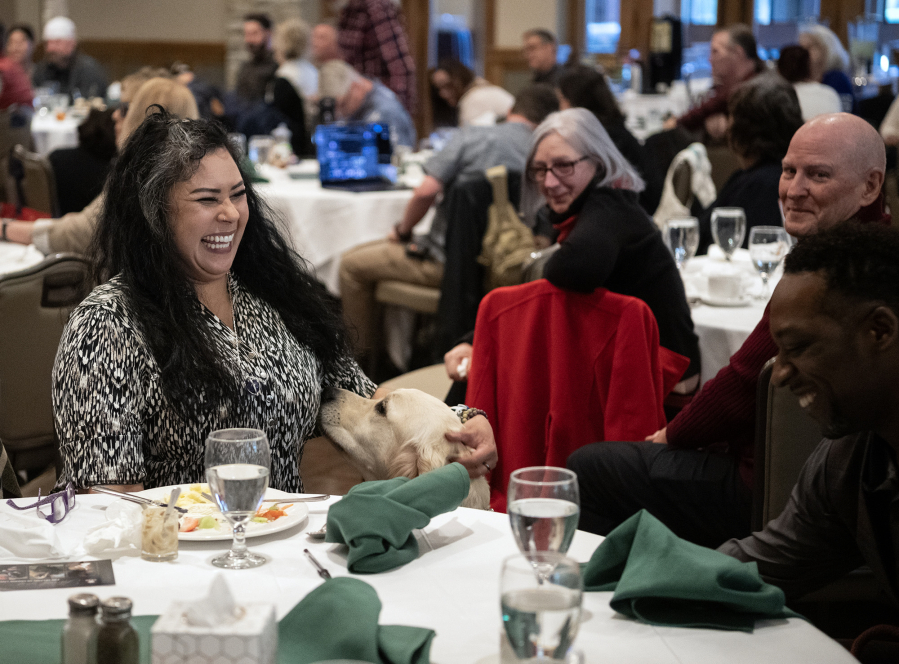 Veteran Jenet Conover, left, laughs and scratches the head of her service dog Huck on Friday during a Northwest Battle Buddies graduation ceremony at Royal Oaks Country Club in Vancouver. The organization gave away its 300th dog to a veteran at the ceremony. (Taylor Balkom/The Columbian)