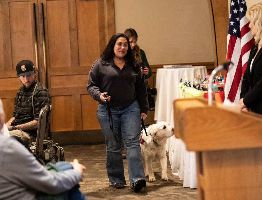 Veteran Rachel Lopez, center, walks to the front of the room with her service dog Cinder on Friday during a Northwest Battle Buddies graduation ceremony at Royal Oaks Country Club in Vancouver. The organization gave away its 300th dog to a veteran at the ceremony. (Photos by Taylor Balkom/The Columbian)