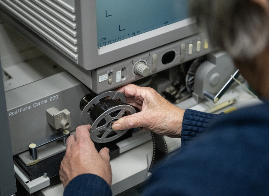 Clark County Genealogical Society member Jane Germann works to put a Lacamas News microfilm reel into a projector Friday at the Clark County Genealogical Society. The donated collection includes 47 reels of the <a href="https://www.camaspostrecord.com/">Camas-Washougal Post-Record</a> and one reel of the Lacamas News. (Taylor Balkom/The Columbian)