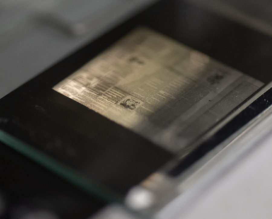 A slide of microfilm containing a page of the Lacamas News from the late 1800s sits above a light Friday at the Clark County Genealogical Society. The Camas Public Library recently donated its historical newspaper microfilm collection to the organization. (Taylor Balkom/The Columbian)
