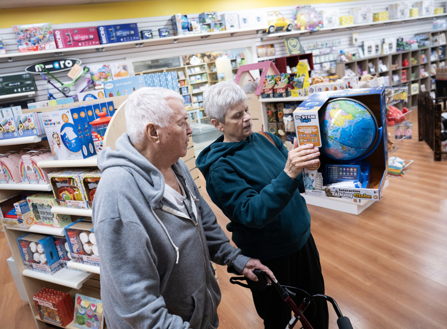 Shoppers Lyle, left, and Diana Smith look at a globe as a potential gift Thursday at Kazoodles Toys & Gifts in east Vancouver. (Photos by Taylor Balkom/The Columbian)