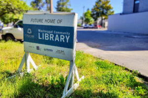 A sign sits in front of the future Washougal library site in downtown Washougal on May 27. (Doug Flanagan/The Columbian files)