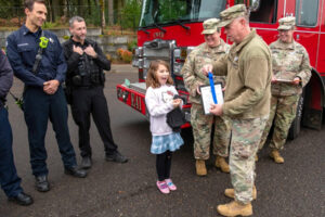 Oregon Army National Guard Lt. Col. Eric Christensen presents a medal to Shelbie McQueen, 8, at Woodburn Elementary School in Camas on Dec. 3. (John Hughel/Oregon Military Department)