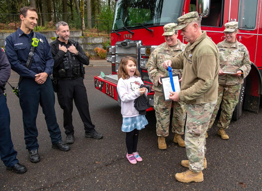 Oregon Army National Guard Lt. Col. Eric Christensen presents a medal to Shelbie McQueen, 8, at Woodburn Elementary School in Camas on Dec. 3. (John Hughel/Oregon Military Department)