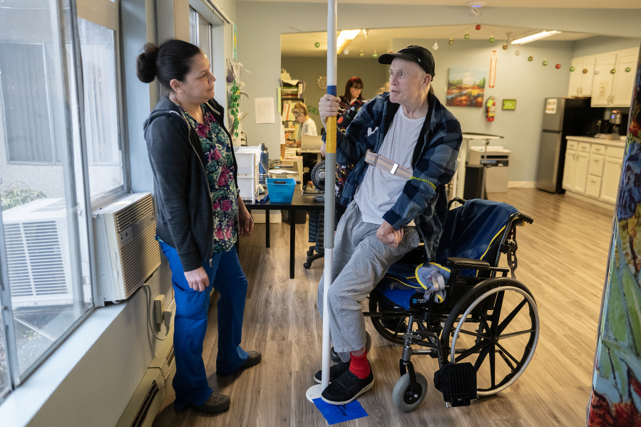 Melissa Allmaras of Vancouver Specialty and Rehabilitation Care, left, joins resident Danny Ellefson as he works on strength and flexibility exercises Dec. 4. In the past 10 years, Washington has lost 12.27 percent of its nursing facilities, or one closure every four months. Vancouver has had only one closure in the past 10 years, but Medicaid cuts could cause more. (Photos by Amanda Cowan/The Columbian)