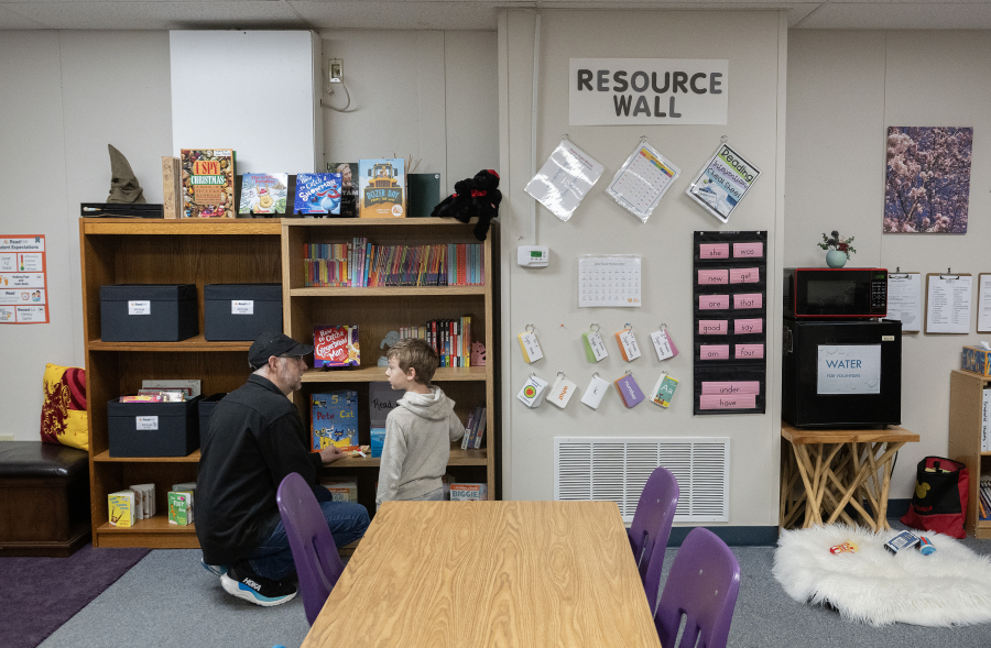 Reading mentor Lee Campen, left, helps third-grader Kellin Bartholomew, 8, select a book during a Read Northwest session Dec. 8 at Hathaway Elementary School. From sounding out words to reading chapter books, Clark County children are getting extra help with their reading through Vancouver nonprofit Read Northwest.