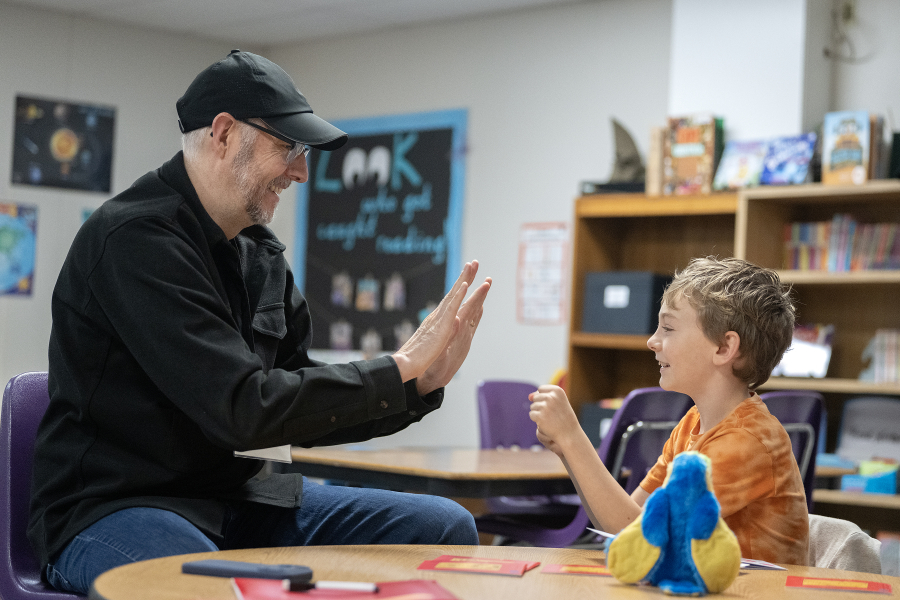 Reading mentor Lee Campen, left, shares some encouragement with third-grader Kellin Bartholomew, 8, during a Read Northwest session Dec. 8 at Hathaway Elementary School. (Amanda Cowan/ The Columbian)