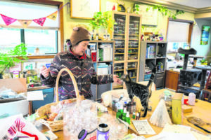 Yvonne Yeh Gee reaches out to touch her rescue cat, Barney, in her huge craft studio on Dec. 19. The room is the site of many workshops hosted through Gee&rsquo;s nonprofit wellness collective, Embrace Qi. (Taylor Balkom/The Columbian)