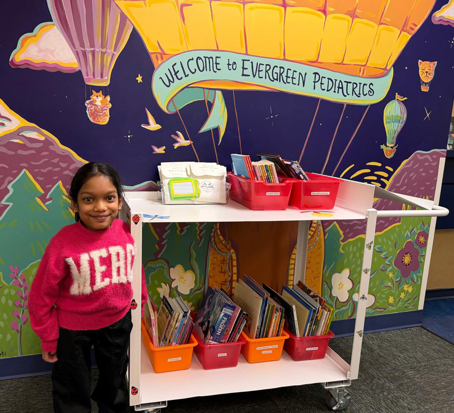 Nysa Vinod, a 14-year-old Camas eighth-grader, stands next to one of her Stories and Smiles carts in an Evergreen Pediatrics Clinic location in Vancouver. (Vinod Vijayan)