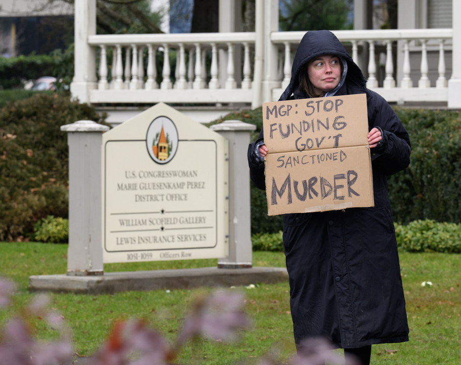 Morgan Rumble of Ridgefield holds a sign Jan. 28 outside the offices of U.S. Rep. Marie Gluesenkamp Perez in Vancouver. (Taylor Balkom/The Columbian)