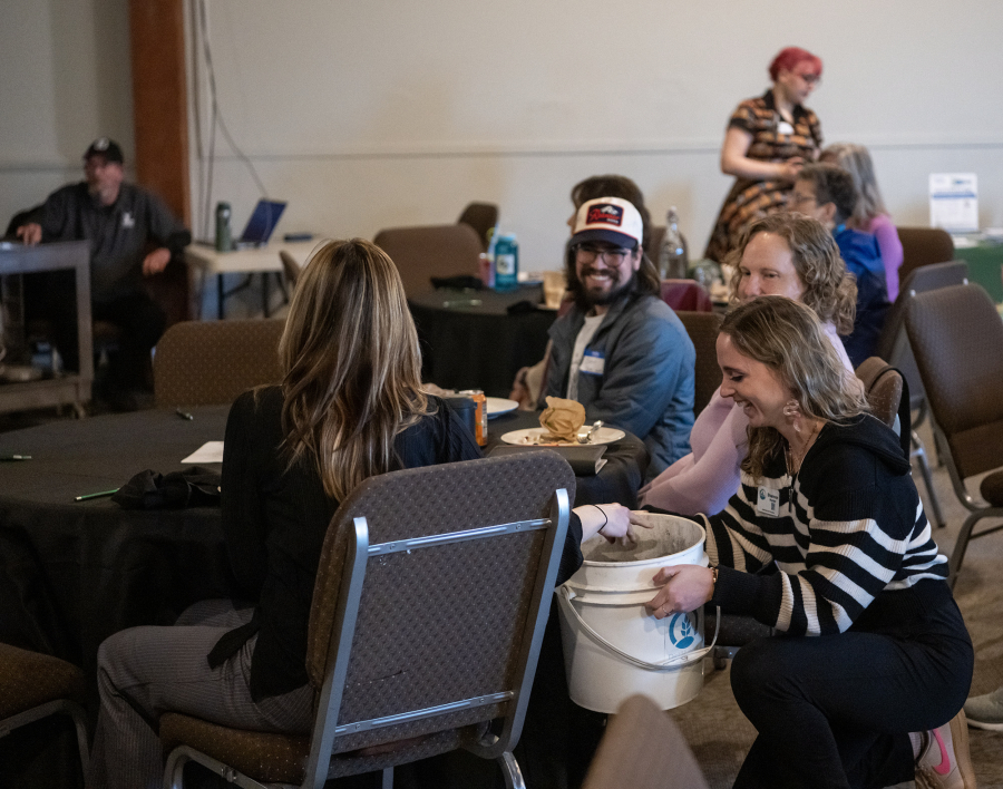 Clark County Public Works outreach specialist Shannon Hunter, bottom right, carries a bucket of compost to tables for people to smell and feel Thursday at Clark County&rsquo;s We Compost celebration at Real Life Foursquare Church in Vancouver. Now in its fourth year, the program collected over 180,000 pounds of food waste in 2025. (Taylor Balkom/ The Columbian)