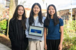 Camas High School sophomores Liya Zhao, from left, Chloe Luo and Alyssa Wong stand for a portrait with the home page of their cancer screening app pulled up Wednesday in downtown Camas. The trio were named the winners of the 2025 Congressional App Challenge for Washington&rsquo;s 3rd District. (Taylor Balkom/The Columbian)