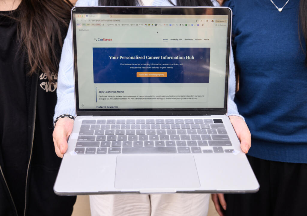 Camas sophomore Chloe Luo holds out a laptop with the home page of the cancer screening app she developed with classmates Alyssa Wong and Liya Zhao pulled up March 4 in downtown Camas. The trio were named the winners of the 2025 Congressional App Challenge for Washington&rsquo;s 3rd District. (Taylor Balkom/The Columbian)