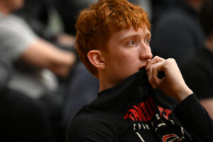 Camas senior Ethan Harris watches from the bench Friday, as a lingering foot injury kept him from playing. (Taylor Balkom/The Columbian)