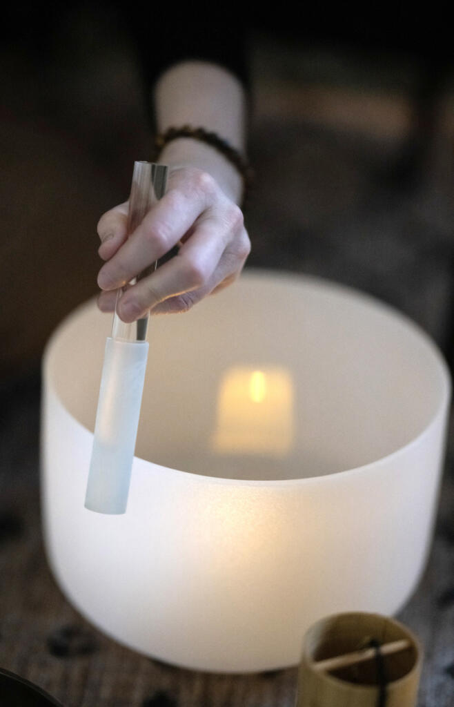 Andrea Kintzley uses a silicone-coated mallet to coax healing tones from a crystal singing during a demonstration on March 10. She plays a set of seven singing bowls for sound bath sessions, as well as an array of other instruments like a gong, Tibetan metal bowls and chimes. She said she&rsquo;s seen a real upsurge in interest in sound baths in recent years. (Taylor Balkom/The Columbian)