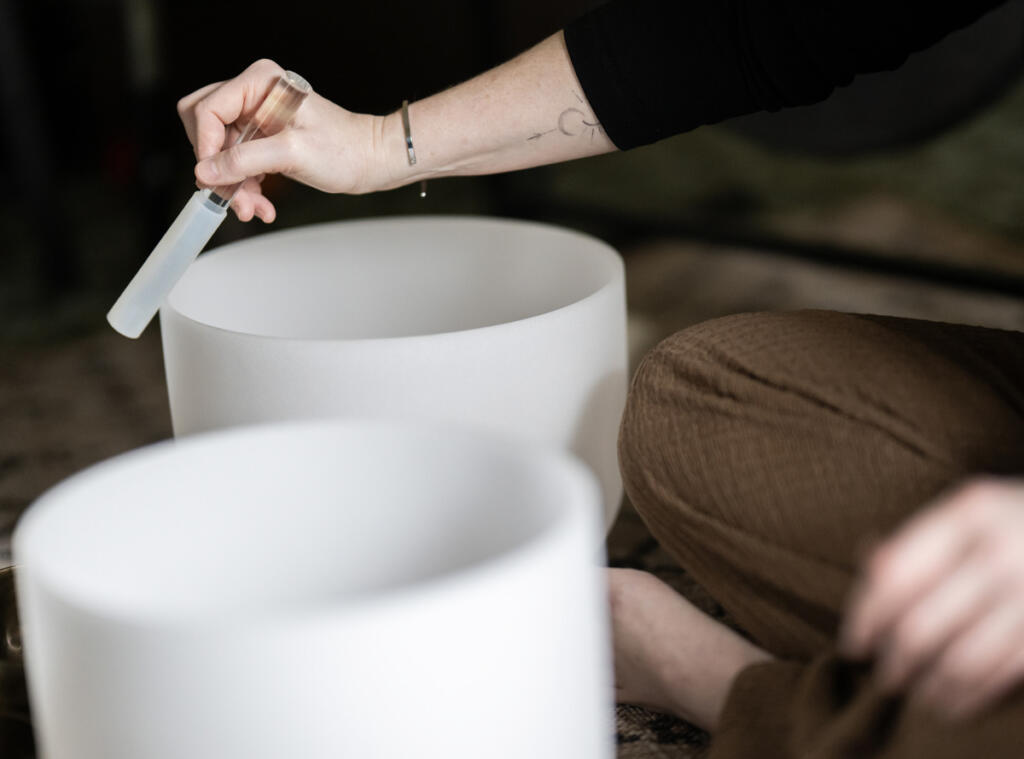 Andrea Kintzley demonstrates crystal singing bowls and other sound therapy instruments on March 10 at Soul Space Wellness in the O.O. Howard Building. She uses a silicone-coated mallet to produce different tones and vibrations which can relax the body. (Taylor Balkom/The Columbian)