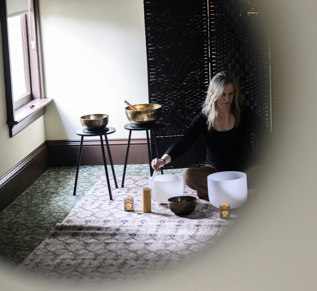Andrea Kintzley demonstrates crystal singing bowls on March 10, 2026, at Soul Space Wellness in the O.O. Howard House. Everybody hears the same thing during a sound bath, Kintzley said, but each person experiences it differently. (Taylor Balkom/The Columbian)