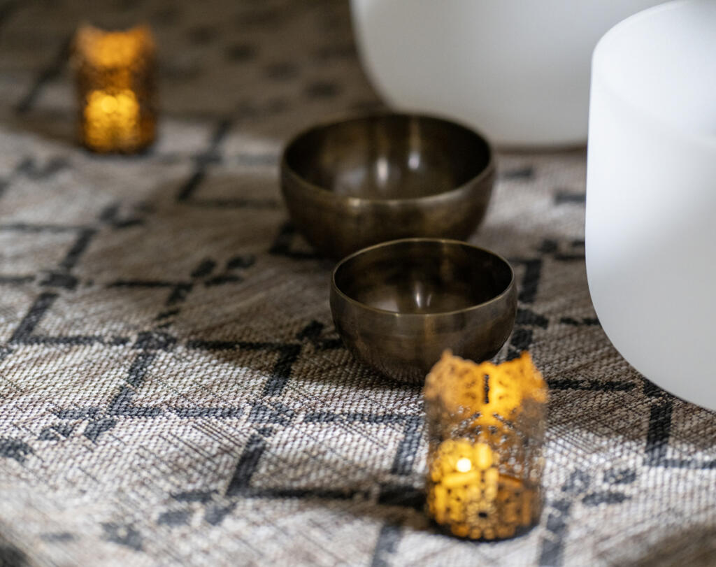 Tibetan singing bowls sit on a rug March 10, 2026, at Soul Space Wellness in the O.O. Howard Building. Studio owner Andrea Kintzley plays these small metal bowls as well as the large, white crystal bowls during sound baths. The tones and vibrations are believed to promote relaxation. (Taylor Balkom/The Columbian)