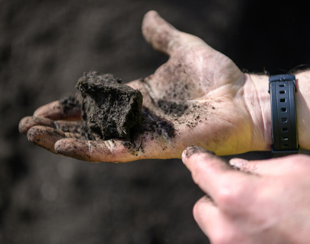 Dirt Hugger co-founder Pierce Louis clumps together a handful of compost. The company uses yard and food waste from Vancouver and Ridgefield to make nutrient-rich compost. (Taylor Balkom/The Columbian)