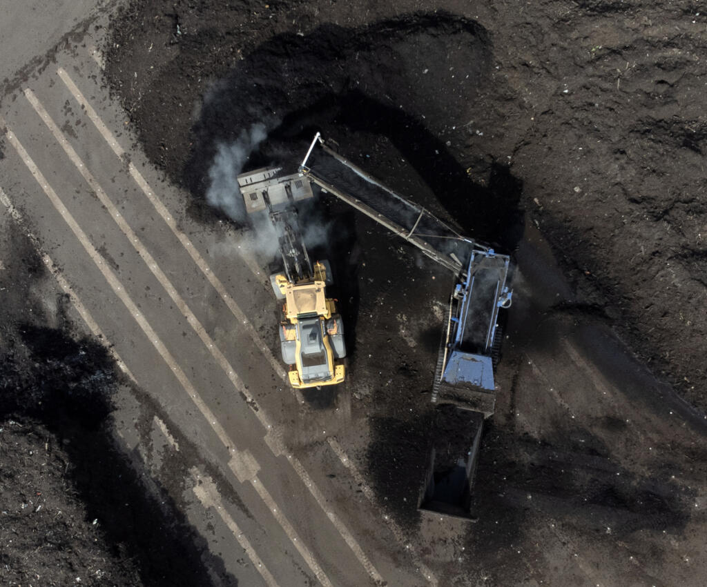 A front loader moves compost material next to a conveyor belt March 20 at the Dirt Hugger composting facility in Dallesport. (Taylor Balkom/The Columbian)
