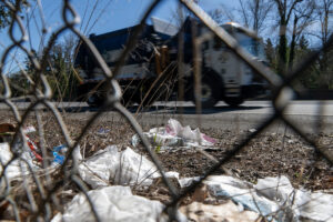 A dump truck drives past trash on the side of state Highway 14 on March 27. (Taylor Balkom/The Columbian)