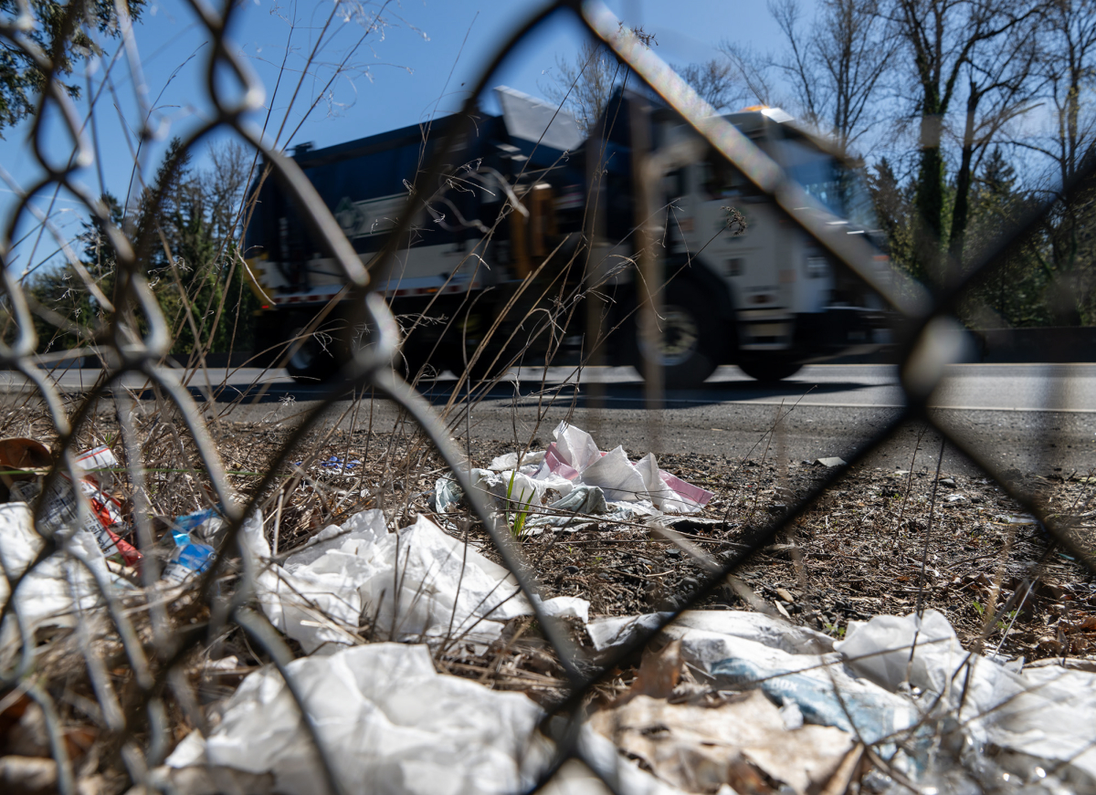 A dump truck drives past trash on the side of state Highway 14 on March 27. (Taylor Balkom/The Columbian)