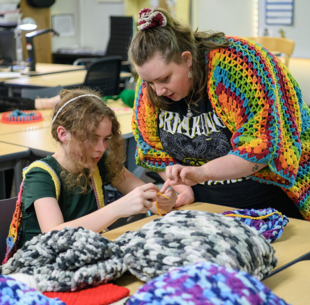 Club leader Bailey Navarro, right, works with sixth-grader Bethany Raby during a crochet club meeting at Pacific Middle School. (Taylor Balkom/The Columbian)