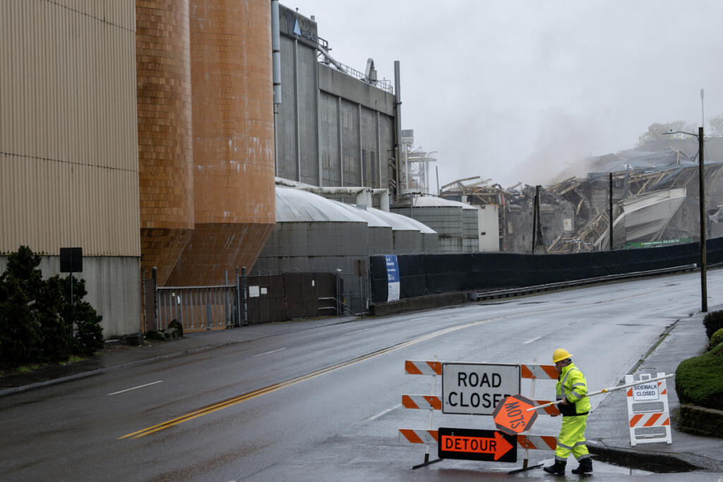 A worker reopens the road in front of the site of the controlled boiler fall at the Georgia-Pacific Camas Mill on Wednesday morning. The project required detours on portions of Sixth and Seventh avenues, which were temporarily closed before, during and a few minutes after the demolition. (Amanda Cowan/The Columbian)