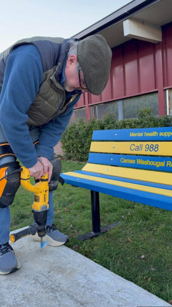 Camas-Washougal Rotarian Richard Renton drills into a concrete slab to install a &ldquo;buddy bench&rdquo; at Liberty Middle School in Camas. (Contributed by George Capacci)