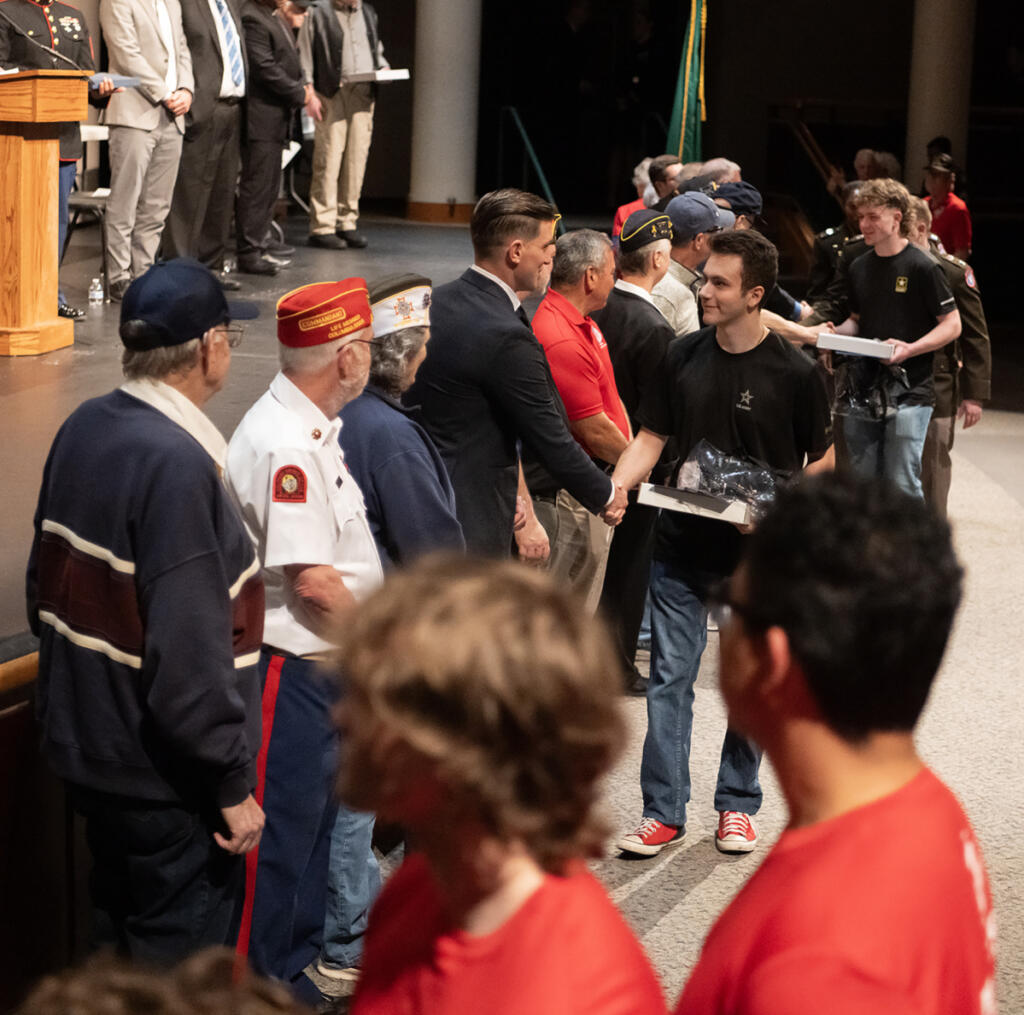 Army recruit Isaiah Trout, center, shakes hands while recruits for the Marines, in red, wait to walk across the stage April 22 during an event for future military service members at Skyview High School. (Photos by Taylor Balkom/The Columbian)