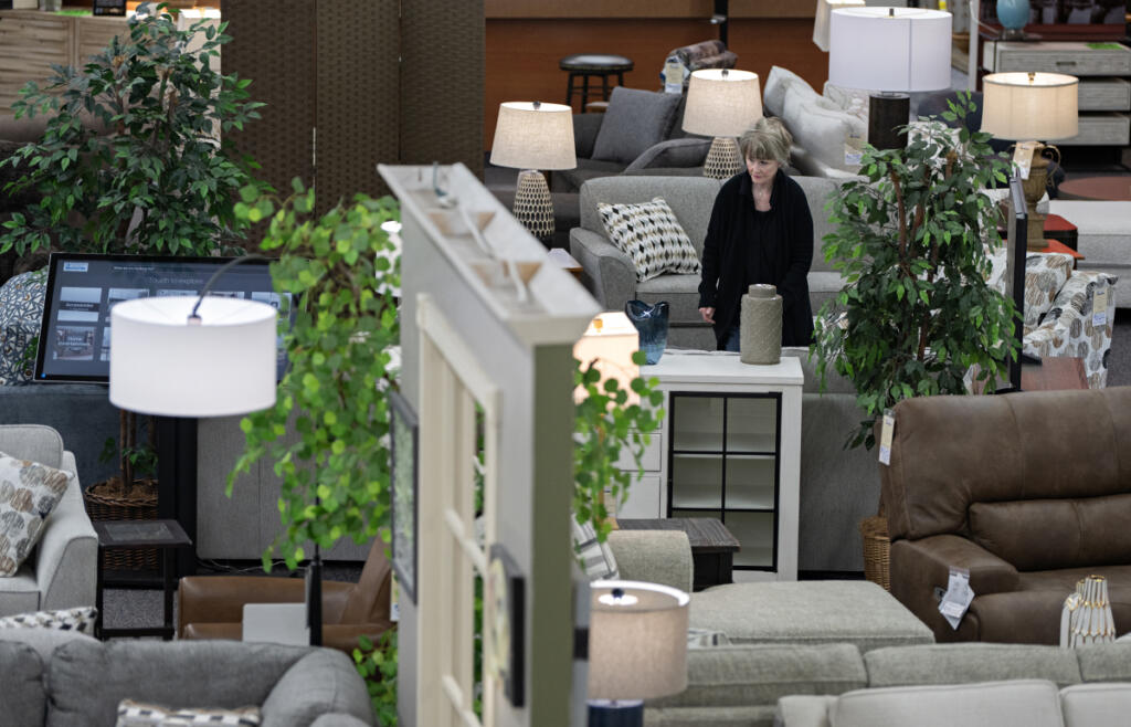 Molly Fletcher of One Stop Home Furnishings in Camas prepares the showroom for customers on April 20. Furniture stores are facing difficulties with uncertainty, slumping demand and rising freight costs. (Amanda Cowan/The Columbian)