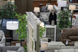 Molly Fletcher of One Stop Home Furnishings in Camas prepares the showroom for customers on April 20. Furniture stores are facing difficulties with uncertainty, slumping demand and rising freight costs. (Amanda Cowan/The Columbian)