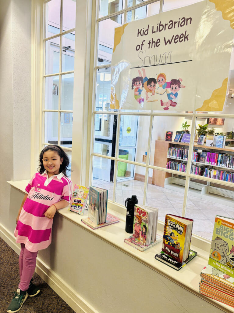 Shayaa Maharjan, a 7-year-old Woodburn Elementary School student, poses for a photo next to her Kid Librarian display at the Camas Public Library in March. (Contributed by Sudin Maharjan)