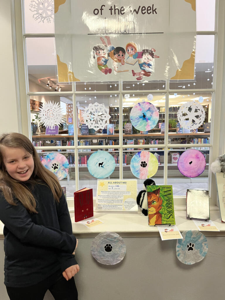 Lilah Meier, a 9-year-old Helen Baller Elementary School student, poses for a photo next to her Kid Librarian display at the Camas Public Library in December. (Contributed by Liisa Meier)