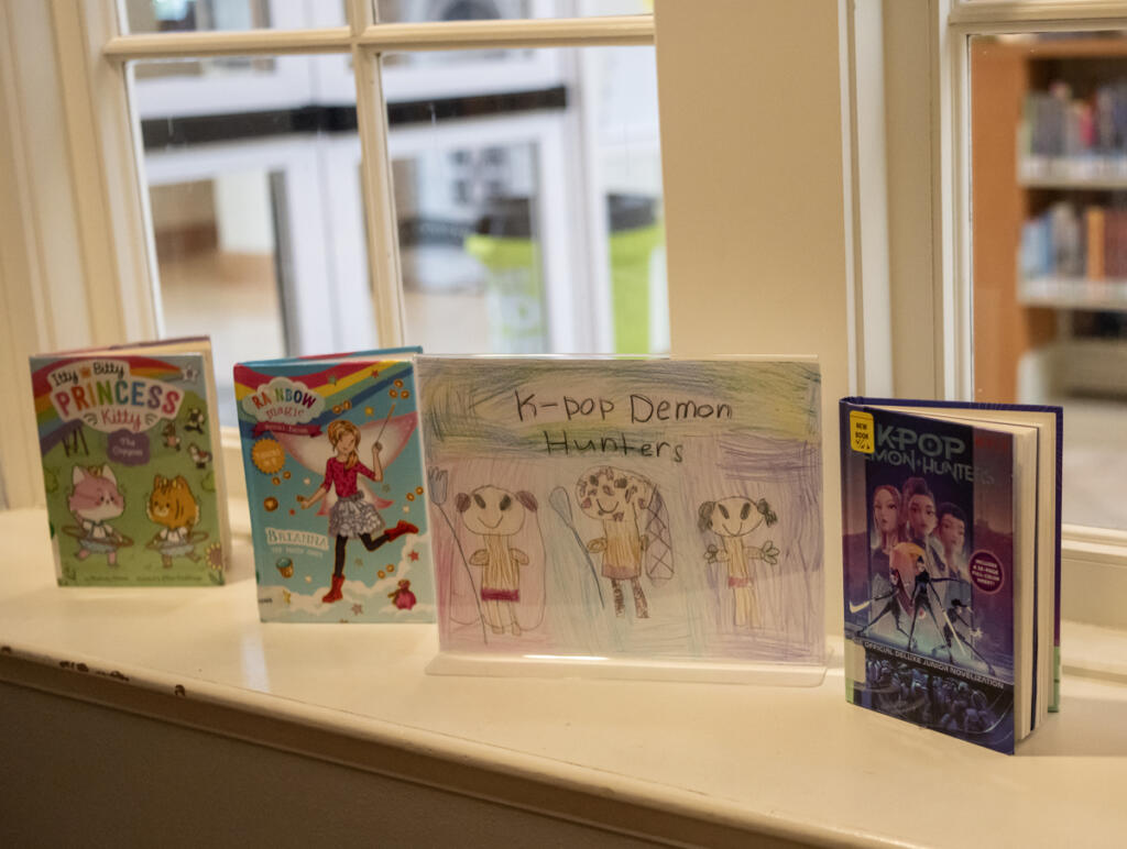 Books and a colored pencil drawing sit in a display April 27 at the Camas Public Library. (Taylor Balkom/The Columbian)