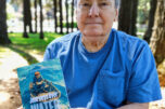 Washougal resident David Knight holds a copy of his memoir, &ldquo;Journeys Over Water,&rdquo; on May 4 at Hathaway Park in Washougal. (Doug Flanagan/The Columbian)