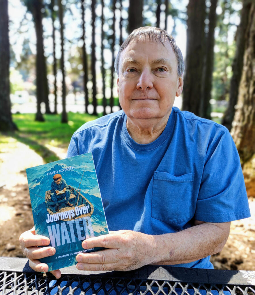 Washougal resident David Knight holds a copy of his memoir, &ldquo;Journeys Over Water,&rdquo; on May 4 at Hathaway Park in Washougal. (Doug Flanagan/The Columbian)