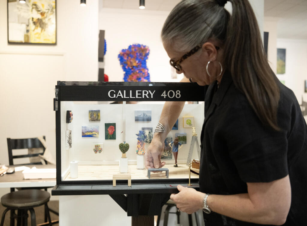 Gallery curator Lara Blair sets up a small bench inside a miniature gallery Wednesday at Gallery 408 in Camas. (Taylor Balkom/The Columbian)