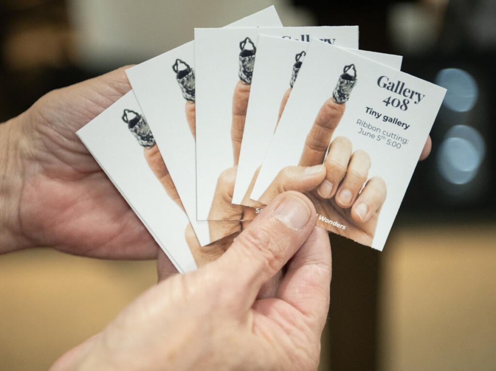 Owner Kim Nickens holds miniature posters for the grand opening of a mini art gallery Wednesday at Gallery 408 in Camas. The mini-gallery will be included on a map produced by the Worldwide Sidewalk Joy Project, which celebrates miniature art installations around the world. (Taylor Balkom/The Columbian)