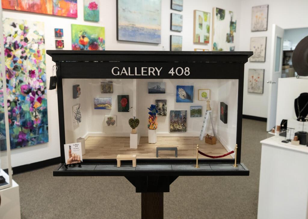 A miniature Gallery 408 sits on a stand inside the regular-sized gallery Wednesday at Gallery 408 in Camas. Gallery 408 co-owners, their husbands and Camas miniaturist Lara Blair built the mini-gallery as part of the Worldwide Sidewalk Joy Project, which celebrates miniature art installations around the world. (Taylor Balkom/The Columbian)